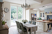 Dining table with wicker chairs in open plan kitchen of Amberley family home West Sussex England UK