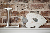 Letter 'L' and fish with exposed brick on shelf in Brighton home, East Sussex, England, UK