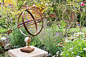 Rusty metal garden ornament on plinth in garden of Amberley home West Sussex UK