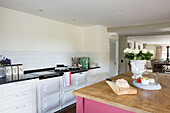 Cut roses and loaf on wooden kitchen island in Petworth farmhouse kitchen West Sussex Kent