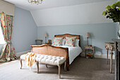 Co-ordinating fabrics in light blue bedroom with wicker bed Petworth farmhouse West Sussex Kent