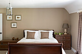 Co-ordinating brown fabrics on polished wooden double bed in Petworth farmhouse West Sussex Kent