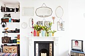 Cut flowers on mantlepiece with mirrors and recessed shelving in London family home,  England,  UK