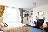 Vintage suitcases at fireplace in bright bedroom of London family home,  England,  UK