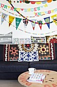 Wanddekoration über marineblauem Sofa mit bestickter Decke in Londoner Familienhaus, England, UK