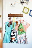 Dresses hang on wall hook in child's nursery,  London family home,  England,  UK