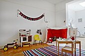 Striped rug and playhouse in playroom of London family home  England  UK