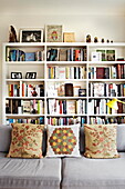 Bücherregal und Sofa mit Polstern in einem Londoner Einfamilienhaus England UK