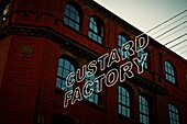 Großer Schriftzug 'CUSTARD FACTORY' in Neonlichtern vor einem Wohnhaus Birmingham UK