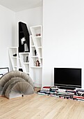 TV and books with wall mounted shelving unit in living room of contemporary London home   England   UK