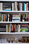 Books and glassware on shelves in contemporary London home   England   UK