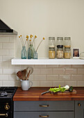 Storage jars and wooden spoons with vegetables on wooden worktop in contemporary London kitchen   England   UK