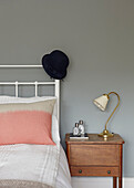 Hat on white headboard with wooden bedside cabinet in contemporary London home   England   UK