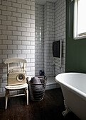 Freistehende Roll-Top-Badewanne mit Vintage-Radio im weiß gefliesten Badezimmer einer modernen Londoner Wohnung England UK