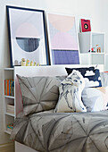 Headboard shelving with artwork and grey bed covers in bedroom of London family home,  England,  UK