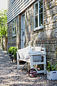 Bench at gravel exterior of stone  brickwork and weatherboard rural United Kingdom home