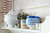 Blue and white ceramic bowls with cut flowers and serving dish on shelf in UK farmhouse kitchen