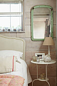 Light green mirror at panelled bedside in UK farmhouse
