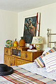 Ornaments on vintage wooden bedside cabinet with striped cushions in Brabourne farmhouse,  Kent,  UK