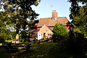 Schattige Gartenmöbel und Backsteinfassade des Bauernhauses von Brabourne, Kent, Großbritannien