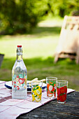 Vintage bottle and plates on picnic table in Brabourne garden,  Kent,  UK