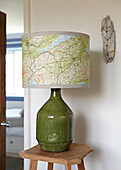 Map lampshade on green base with wooden side table in hallway of Bolton home,  Greater Manchester,  England,  UK