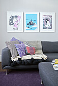 Framed prints above sofa with cushions in living room of London townhouse  England  UK