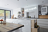 Weiße offene Einbauküche mit Holztisch in einem Londoner Stadthaus England UK