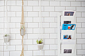 Rope plant hangers and magazine rack in white tiled bathroom of London apartment  UK