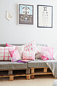 Assorted pink cushions on sofa made from wood pallets in Alloa home  Scotland  UK