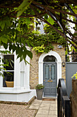 Graue Haustür mit gepflastertem Fußweg und Vorplatz aus Kies London England UK