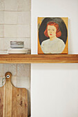 Portraiture on shelf with side plates and chopping board in kitchen of London home  UK