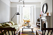 Runder Spiegel über Marmorkamin mit Vintage-Möbeln in einem Londoner Haus UK