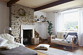 Exposed stone chimney breast and seating with firewood in West Yorkshire living room  UK