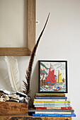 Framed artwork and feather with stack of books on mantlepiece in Berwick Upon Tweed home  Northumberland  UK