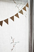 Brown paper bunting in window with muslin curtains in London home  UK