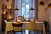 Lit candles and pendant lights on dining table in London home  UK