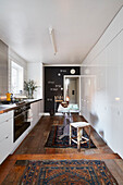White storage and wooden floors with Norse vintage rugs in Rochester galley kitchen  Kent  UK