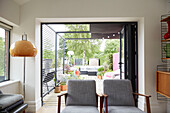 Pair of grey retro style armchairs with view to garden terrace from modernised Preston home  Lancashire  England  UK