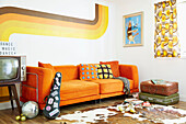 Orange sofa with vintage suitcases in retro styled living room of East Riding of Yorkshire home  England  UK
