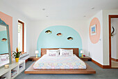 Low wooden platform bed and mattress with novelty fish ornaments in East Riding of Yorkshire home  England  UK