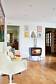 Pair of cream chairs and lit woodburner in York home  England  UK