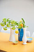 Cut flowers in vases on yellow table in modern kitchen  London  UK