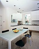 Modern white fitted kitchen diner with frosted glass table