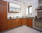 Corner of modern fitted kitchen with dark wood units