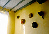Sunny yellow wall detail showing ceiling and beams with display of hats