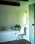 Gefliestes Badezimmer im französischen Stil mit Klappstuhl und Handtüchern