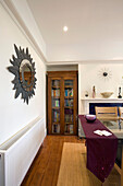 Leaf surround mirror in dining room with glass fronted cabinet in New Malden home, Surrey, England, UK