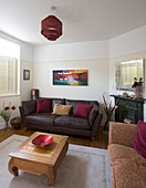 Kunstwerk über einem braunen Ledersofa in einem Haus in New Malden mit einem Couchtisch aus Holz, Surrey, England, UK