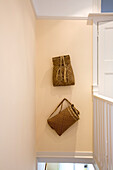 Two natural fibre bags hang above staircase in New Malden home, Surrey, England, UK